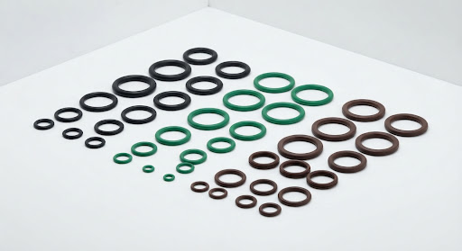 Black, green, and brown FKM rubber O-rings arranged on a white surface